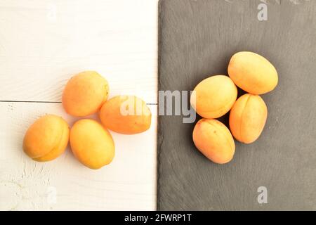 Diverse albicocche di ananas gialle mature, primo piano, su tavola di ardesia e tavolo di legno bianco, vista dall'alto. Foto Stock