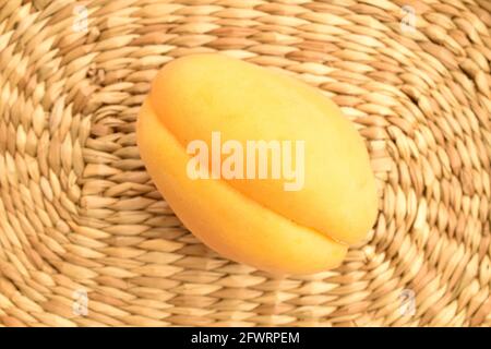 Una albicocca di ananas gialla, macro, su un tappetino di paglia, vista dall'alto. Foto Stock