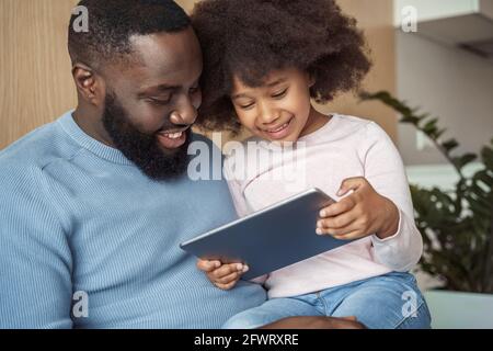 Ritratto closeup di papà sorridente felice e figlia che guarda il video su tablet Foto Stock