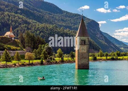 Pescatore nella sua barca vicino al campanile sommerso nel lago di Resia, Curon, Alto Adige, Italia Foto Stock