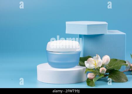 Cura cosmetica della pelle del viso con figure geometriche e fiori di albero di apple su sfondo blu Foto Stock