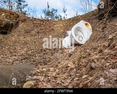 Lettiera WC. Inquinamento della foresta da rifiuti domestici sulla natura. Un mucchio di spazzatura. WC in ceramica rotto scartato in una palude con un altro concetto di ambiente inquinante Foto Stock