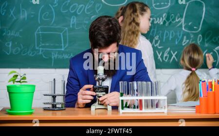 Insegnante di biologia. L'uomo ha sopportato il lavoro dell'insegnante con il microscopio e le provette di prova in classe di biologia. Spiegare la biologia ai bambini. Giochi di biologia Foto Stock