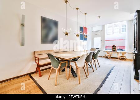 Design moderno di sala da pranzo appartamento con tavolo in legno e. sedie con panca sotto lampade a sospensione Foto Stock