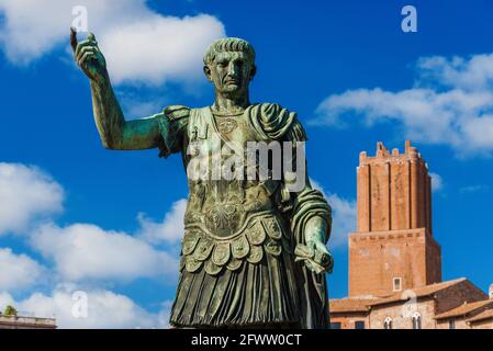 Imperatore Traiano di Roma antica statua con torre medievale Di Militia sullo sfondo lungo la Via dei fori Imperiali in Il centro storico di Roma Foto Stock