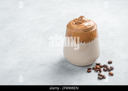 Caffè e chicchi di caffè Dalgona su sfondo grigio. Foto Stock