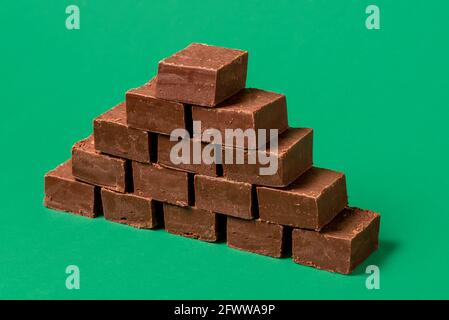 Stack di cioccolato fondente fatto in casa su un tavolo verde. Pile di deliziose barrette di cioccolato isolate su uno sfondo verde. Foto Stock