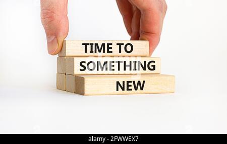 È il momento di un nuovo simbolo. Blocchi di legno con parole 'Time to something new' su uno sfondo bianco bello. Mano uomo d'affari. Affari, tempo ad alcuni Foto Stock