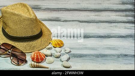 Vacanze estive, concetto di sfondo angolato con spazio di copia per il testo. Cappello Panama, conchiglie spiaggia su un tavolo di legno bianco personalizzato Foto Stock