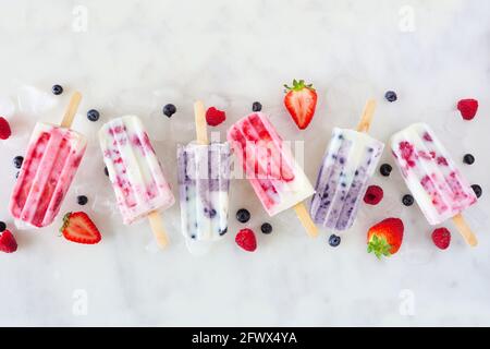 Gruppo di gelato assortiti allo yogurt con frutta a bacca. Vista dall'alto in fila su uno sfondo di marmo bianco. Foto Stock