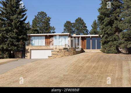 Architettura che mostra l'esterno di una moderna casa in stile ranch MCM della metà del secolo con un prato anteriore marrone dormiente. Foto Stock