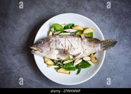 Pesce di cernia fresco crudo su piatto con erbe e spezie per il pesce cotto al vapore Foto Stock