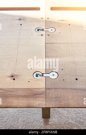 Montaggio di un grande tavolo da pranzo in legno con connettori installati sul piano di lavoro e si sviti all'aperto durante la giornata di sole, vista ravvicinata Foto Stock