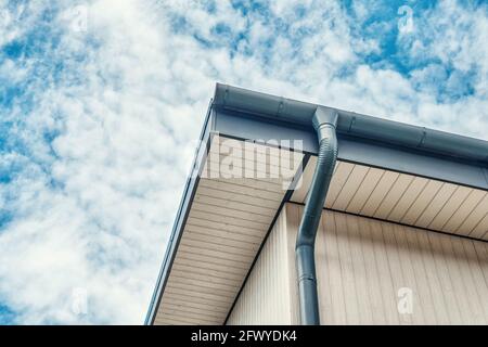 Downpipe in metallo grigio contemporaneo installato sul tetto della nuova edificio con vista nuvolosa giorno vicino Foto Stock