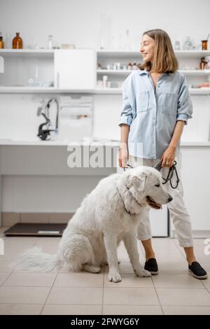 Donna con grande cane bianco in attesa per il veterinario in clinica veterinaria. Concetto di cura degli animali domestici Foto Stock