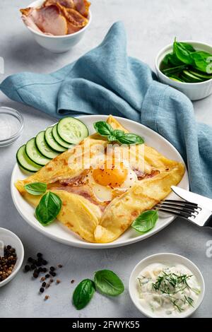 Colazione con pancake, uova, prosciutto e formaggio su sfondo grigio. Foto Stock