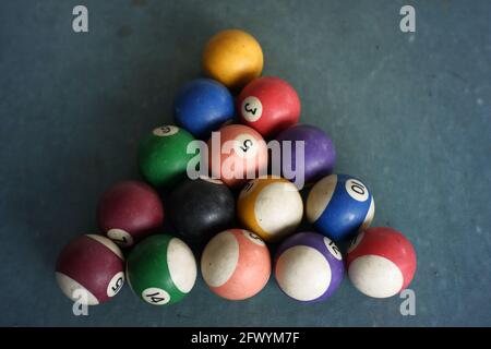 la formazione della sfera del biliardo forma un triangolo. gioco del biliardo usando quindici palle. tavolo di gioco con tappeto blu. palla bianca e bastone di legno sul tavolo Foto Stock