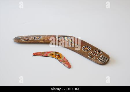 Uno di loro più grande. Boomerang colorati e ornati. Souvenir australiano, fuoco selettivo. Sfondo bianco isolato. Foto Stock