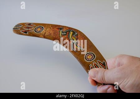 Uomo con boomerang colorato e ornato. Souvenir australiano, fuoco selettivo. Sfondo bianco isolato. Foto Stock