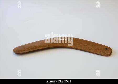 Boomerang colorato e ornato. Souvenir australiano, fuoco selettivo. Sfondo bianco isolato. Foto Stock