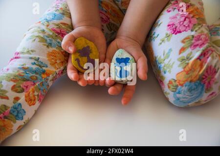 la bambina mostra al padre le pietre che lei ha verniciato a colori Foto Stock