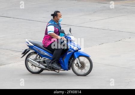 SAMUT PRAKAN, THAILANDIA, 25 2020 LUGLIO, UN uomo con maschera faccia guida una moto Foto Stock