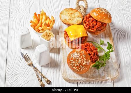 Panini Slippy Joe su brioche panini serviti con patatine fritte su un bordo di legno bianco, primo piano, cucina americana Foto Stock