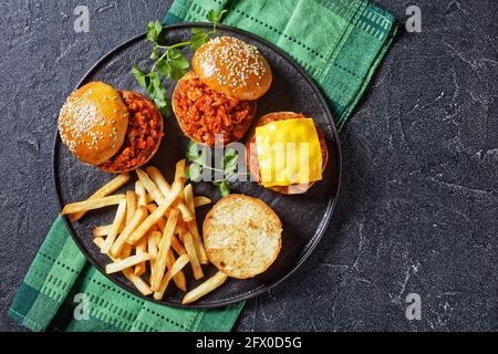 Panini fatti in casa al barbecue Sloppy Joe con patatine fritte su un piatto nero, piatto, spazio libero Foto Stock