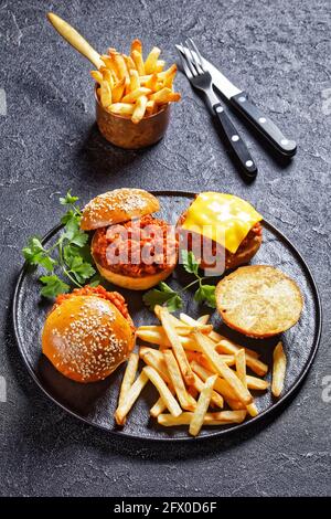 Panini BBQ Sloppy Joe con patatine fritte su un piatto nero, vista verticale, cucina americana Foto Stock