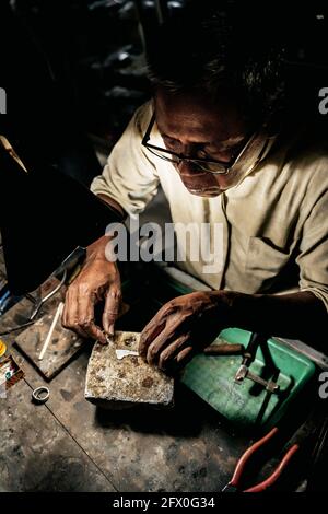 Da sopra l'uomo etnico maturo che lavora alla scrivania intemperie in officina artigianale Foto Stock