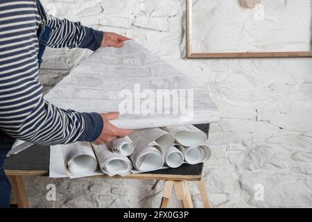 Vista laterale del raccolto anonimo maschio in abbigliamento casual scelta sfondi durante la ristrutturazione in appartamento Foto Stock