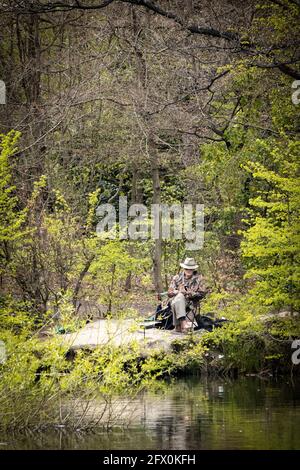 Un solo pescatore sulle rive di un lago locale a Calverley, Yorkshire Foto Stock