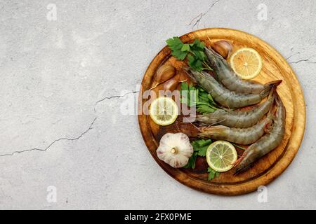 Gamberi crudi serviti su una tavola di legno su uno sfondo di legno chiaro. Vista dall'alto, disposizione piatta Foto Stock