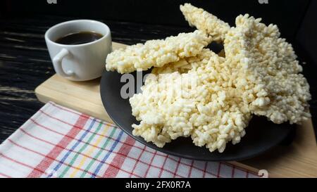 Rengginang o patatine a base di riso glutinoso indonesiano tradizionale con uno sfondo di tavola di legno nero Foto Stock