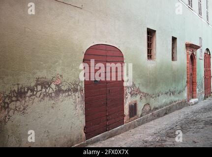 Una vecchia porta in legno in una parete verde di un vecchio edificio (Marche, Italia, Europa) Foto Stock