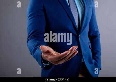 Metà sezione di uomo d'affari afroamericano con la mano imbutita contro sfondo grigio Foto Stock