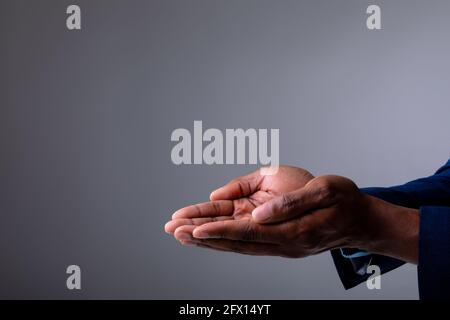 Sezione centrale di uomo d'affari con le mani cupolate su sfondo grigio Foto Stock