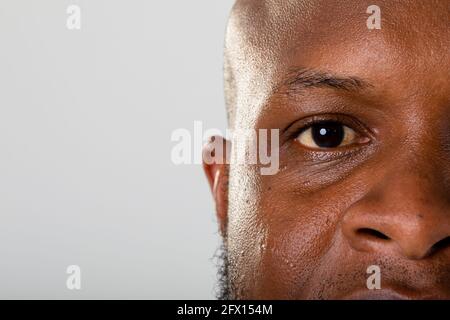Primo piano di occhio di uomo d'affari afroamericano contro il grigio sfondo Foto Stock