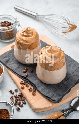 Caffè e chicchi di caffè Dalgona su sfondo grigio. Foto Stock