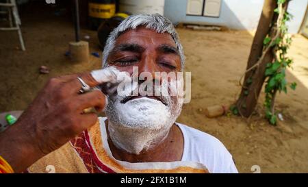 01 gennaio 2021 - Reengus, Sikar, India. Barbiere di strada che rasa un uomo usando una lama di rasoio aperta su una strada in Sikar. Foto Stock