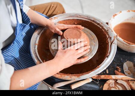 Adulto che forma la greenware nel recipiente con le mani sulla ruota del vasaio Foto Stock