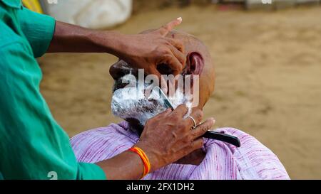 01 gennaio 2021 - Reengus, Sikar, India. Un barbiere lato strada che rade la barba di un uomo all'aperto a Rajasthan, India. Foto Stock