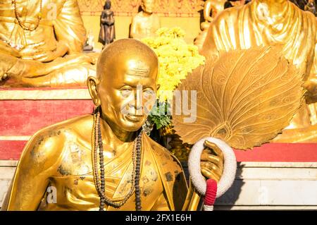 Statua dorata del vecchio monaco buddista con i fiori che si adornano Il santuario di Doi Suthep - antico tempio buddha in Provincia di Chiang mai in Thailandia Foto Stock