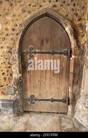 Una vecchia porta in rovere ad arco con lunghe cerniere nere e. una serratura in muratura medievale Foto Stock
