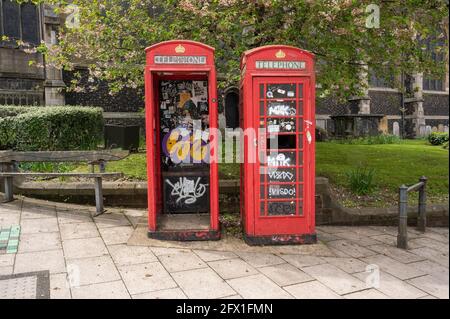 Due scatole telefoniche rosse di derelict vandilizzate l'una accanto all'altra con una porta mancante e il vetro schiacciato Foto Stock