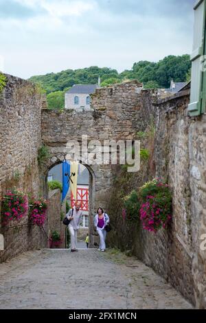 Poterne St Jean, Moncontour, Côtes d'Armor, Bretagna, Francia: Un cancello nelle mura della città, con una coppia turistica che guarda Foto Stock