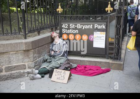 Gli senzatetto dormono al sole mentre chiedono aiuto fuori Bryant Park a 40th Street e 6th Avenue a Manhattan. Foto Stock