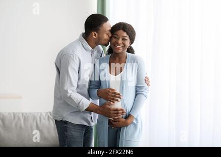 Marito amorevole baciare la sua bella moglie incinta Foto Stock