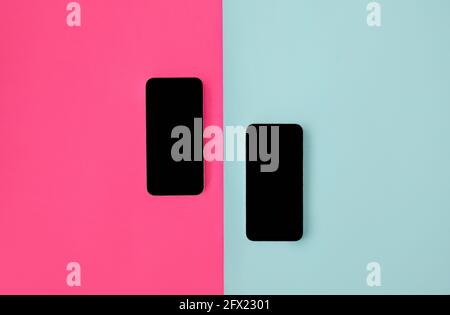 Due smartphone con schermo vuoto su sfondo blu e rosa, vista dall'alto, disposizione piatta Foto Stock