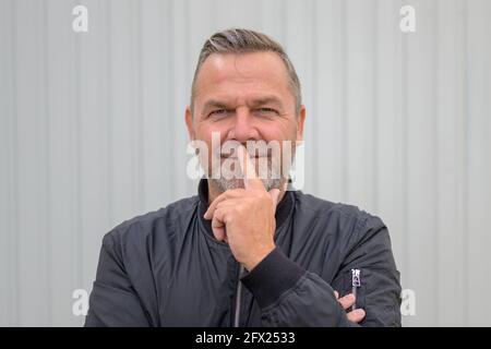 Uomo di mezza età in piedi profondo nel pensiero con il dito al labbra con espressione contemplativa in testa e spalle verticale Foto Stock